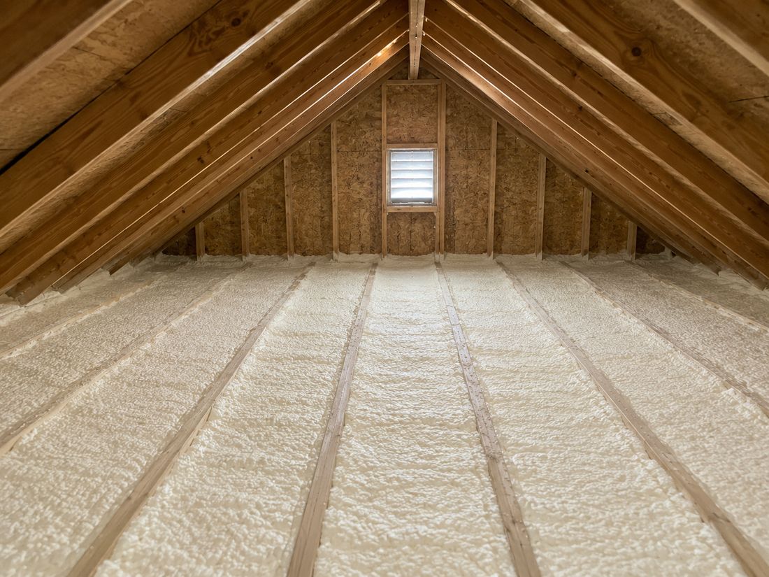 The same attic after a spray foam retrofit, with an even white insulated deck between the joists